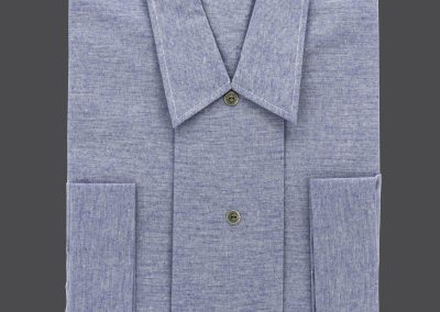 Ein gefaltetes blaues Jeanshemd mit Kn&ouml;pfen ruht elegant auf einem dunklen Hintergrund, begleitet von der subtilen Erscheinung eines deutschen Textes und einem Hinweis auf die Bestattung in der Ecke.